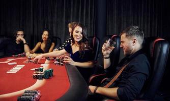 Group of elegant young people that playing poker in casino together photo