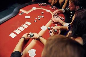 grupo de jóvenes elegantes que juegan al póquer en el casino juntos foto