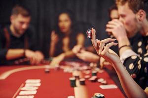 grupo de jóvenes elegantes que juegan al póquer en el casino juntos foto