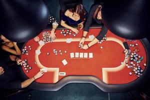 vista superior de jóvenes elegantes que juegan al póquer en el casino foto