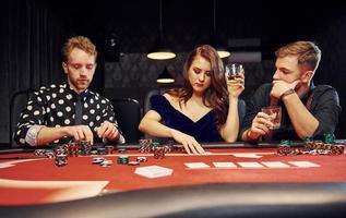 grupo de jóvenes elegantes que juegan al póquer en el casino juntos foto