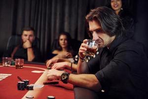 Group of elegant young people that playing poker in casino together photo