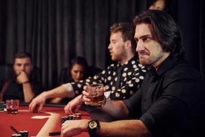 Group of elegant young people that playing poker in casino together photo