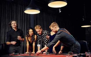 People in elegant clothes standing and playing poker in casino together photo