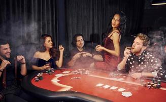 Group of elegant young people that playing poker in casino together photo