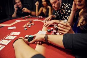 grupo de jóvenes elegantes que juegan al póquer en el casino juntos foto