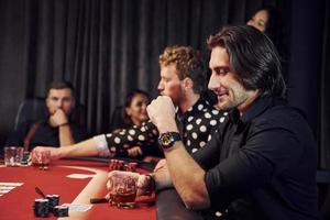 Group of elegant young people that playing poker in casino together photo