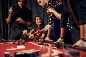 gente con ropa elegante de pie y jugando al póquer en el casino juntos foto