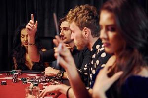 With glasses of drink. Group of elegant young people that playing poker in casino together photo