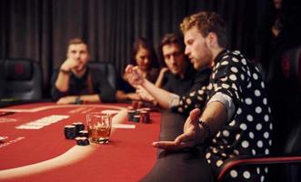 Side view of group of elegant young people that playing poker in casino together photo