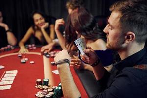 Group of elegant young people that playing poker in casino together photo