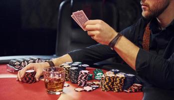 Elegant young man sits in casino and plays poker game photo