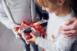 Two little girls holding gift box indoors at holiday christmas time photo