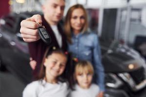 Focused view of man with his family holds keys of new automobile photo