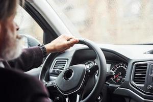 el hombre mayor de moda con ropa elegante está en el coche moderno foto