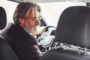 el hombre mayor de moda con ropa elegante está en el coche moderno foto