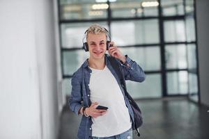 Young student in casual clothes walks indoors with backpack photo