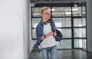 Young student in casual clothes walks indoors with backpack photo