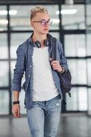 Young student in casual clothes walks indoors with backpack photo