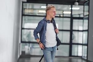 Young student in casual clothes walks indoors with backpack photo