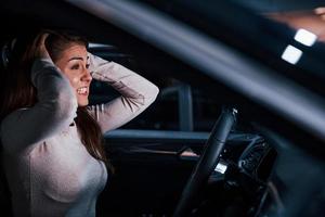 Side view of young woman that gestures inside of brand new modern automobile photo