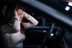 Side view of young woman that gestures inside of brand new modern automobile photo