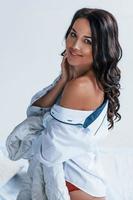 Beautiful young brunette in white coat stands in the studio photo