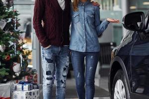 Close up view of lovely couple that standing near car and christmas tree at new year time photo