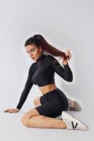 Twerk dancing. Sportive woman in black clothes in the studio against white background photo