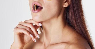 Naked woman in the studio against white background and with pill in mouth photo