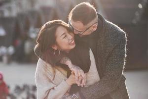 Cheerful multiracial couple embracing each other outdoors in the city. Asian girl with her caucasian boyfriend photo