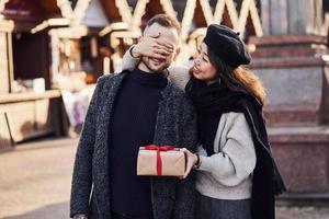 Cute asian girlfriend making surprise and giving gift box to her caucasian man photo