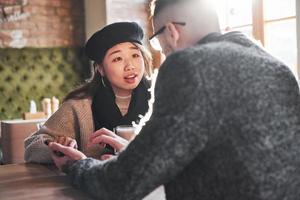 Multiracial couple talking in cafe. Asian girl with her caucasian boyfriend photo