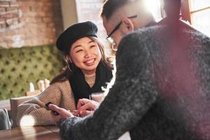 Multiracial couple talking in cafe. Asian girl with her caucasian boyfriend photo