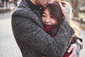 Warming by using red plaid. Happy multiracial couple together outdoors in the city. Asian girl with her caucasian boyfriend photo