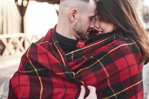 Warming by using red plaid. Happy multiracial couple together outdoors in the city. Asian girl with her caucasian boyfriend photo