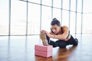 Beautiful sporty woman in sportswear doing stretching by using equipment on the floor photo