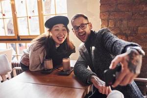 Multiracial couple making selfie in cafe. Asian girl with her caucasian boyfriend photo