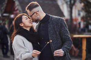 With sparklers in hands. Happy multiracial couple together outdoors in the city photo