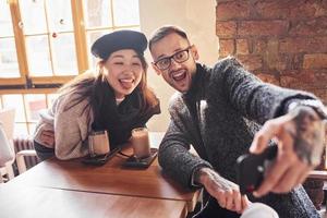 Multiracial couple making selfie in cafe. Asian girl with her caucasian boyfriend photo