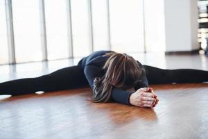Sporty woman in black sportswear lying down on the floor by doing stretching photo