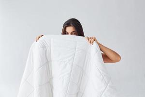 mujer escondida detrás de la toalla en el estudio con fondo blanco foto