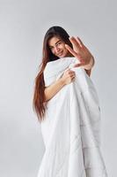 Stop gesture. Woman covering her body by towel in the studio against white background photo