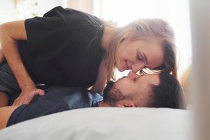 Young married couple kissing each other in bedroom at daytime photo