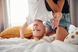 Mother playing and have fun with her son in bedroom at daytime photo