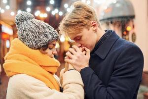 Closeness of the people. Happy young couple in warm clothes is on christmas decorated street together photo