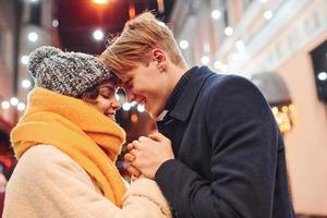 Closeness of the people. Happy young couple in warm clothes is on christmas decorated street together photo