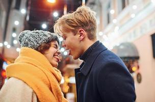 Cute couple in warm clothes have fun on christmas decorated street smiling and have fun photo