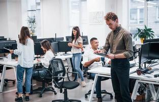 Man in glasses standing in front of his colleagues in the office photo