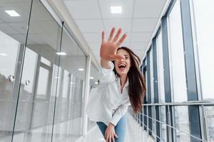 morena con camisa blanca en interiores en aeropuertos modernos o pasillos durante el día foto